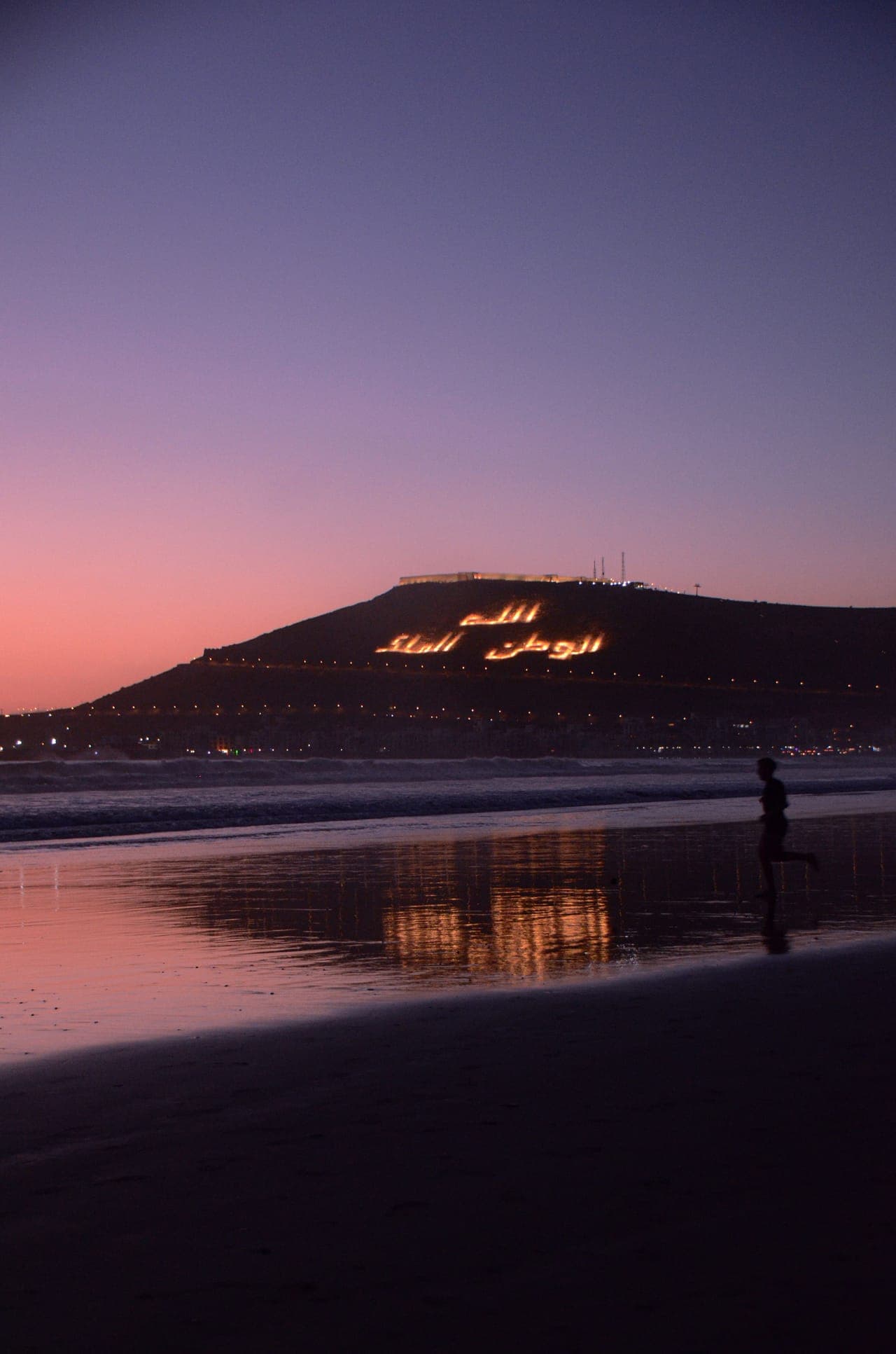 Plage d'Agadir au crépuscule avec les lumières de la colline d'Agadir Oufella